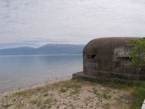View of a historic concrete bunker on the shore of Lake Ohrid with mountains in the background Pogradec Korce County Albania. View of a historic concrete bunker on the shore of Lake Ohrid with mountains in the background Pogradec Korce County Albania.
