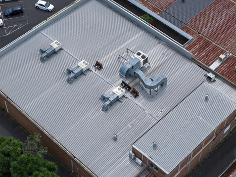 Melbourne VIC Australia 25 September 2026 Aerial view of an industrial factory building roof featuring corrugated metal surfaces multiple HVAC ventilation units and metal ductwork.
