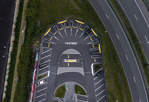 Aerial view of a Fastned electric vehicle charging station with yellow markings and parked cars located next to a highway in Amsterdam Noord Holland Netherlands. Aerial view of a Fastned electric vehicle charging station with yellow markings and parked cars located next to a highway in Amsterdam Noord Holland Netherlands.