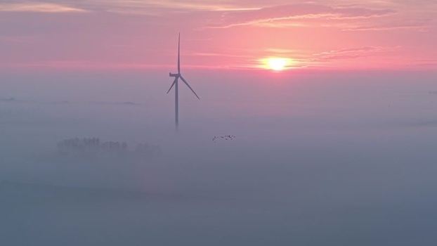Aerial view of a wind turbine in the fog at sunrise Netherlands. Aerial view of a wind turbine in the fog at sunrise Netherlands.