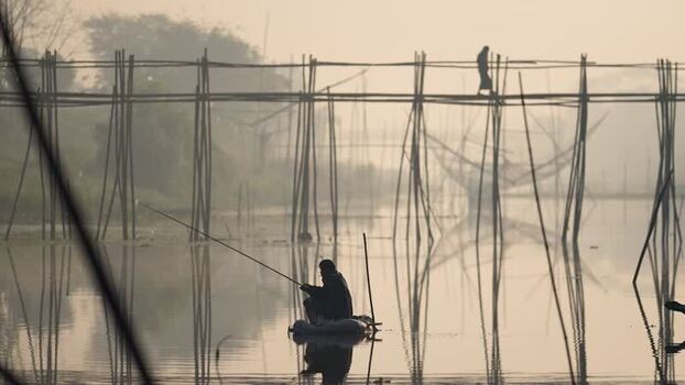 View of a fisherman on a river with a bamboo bridge Bangladesh. View of a fisherman on a river with a bamboo bridge Bangladesh.