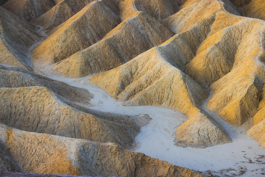 View of the golden hued eroded badlands and ridges of Zabriskie Point in Death Valley National Park United States.