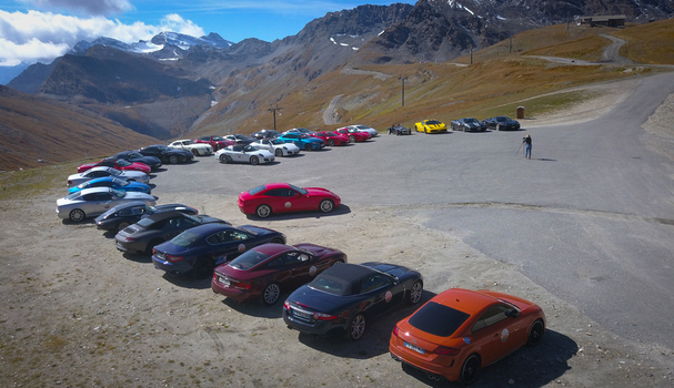 Bonneval sur Arc France 28 September 2019 Aerial view of a vibrant array of cars parked in a semi circle formation against the backdrop of rugged mountains and a clear blue sky. Bonneval sur Arc France 28 September 2019 Aerial view of a vibrant array of cars parked in a semi circle formation against the backdrop of rugged mountains and a clear blue sky.