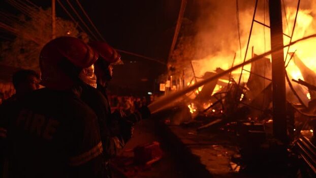 View of firefighters battling a large fire at night Bangladesh. View of firefighters battling a large fire at night Bangladesh.