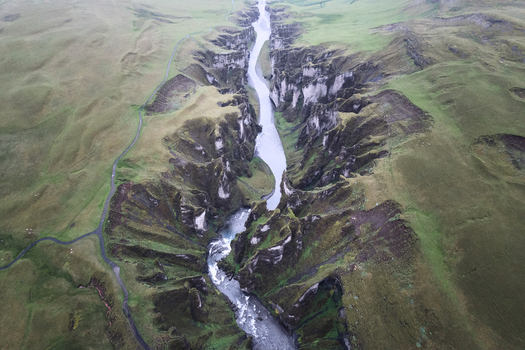 Aerial view of Fjadrargljufur canyon with its winding river and steep moss covered cliffs under a misty sky Skaftarhreppur Iceland. Aerial view of Fjadrargljufur canyon with its winding river and steep moss covered cliffs under a misty sky Skaftarhreppur Iceland.