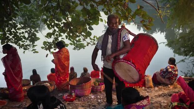 View of a man playing a traditional drum by a river Bangladesh. View of a man playing a traditional drum by a river Bangladesh.