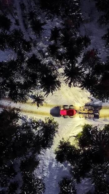 Aerial view of tractor in snowy forest Latvia.