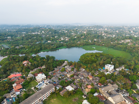 Aerial view of a serene lake surrounded by dense tropical vegetation and residential rooftops in Galle Southern Province Sri Lanka.
