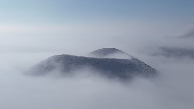Aerial view of a volcanic cone emerging from thick fog Turkiye.