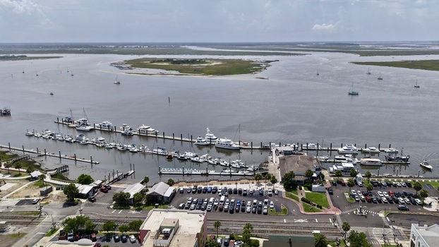 Aerial view of a bustling marina with boats on dark water a busy parking lot and a wide river under a hazy sky Fernandina Beach Florida United States. Aerial view of a bustling marina with boats on dark water a busy parking lot and a wide river under a hazy sky Fernandina Beach Florida United States.