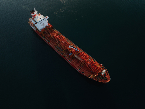 Aerial view of a large red oil tanker ship navigating the calm dark blue waters of the Mediterranean Sea near the port of Augusta Sicily Italy. Aerial view of a large red oil tanker ship navigating the calm dark blue waters of the Mediterranean Sea near the port of Augusta Sicily Italy.