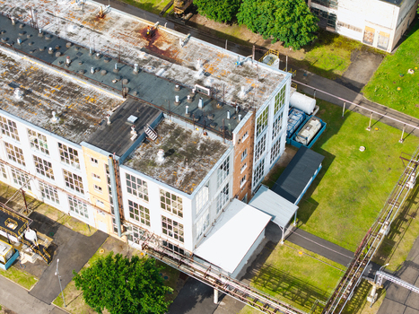 Aerial view of an industrial factory building with a flat roof large windows and surrounding green space in Olaine Olaine Municipality Latvia. Aerial view of an industrial factory building with a flat roof large windows and surrounding green space in Olaine Olaine Municipality Latvia.