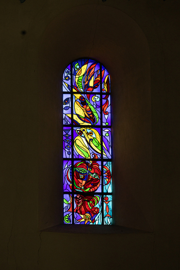 View of a colorful abstract stained glass window inside Ribe Cathedral with vibrant light filtering through the dark stone wall Ribe Denmark. View of a colorful abstract stained glass window inside Ribe Cathedral with vibrant light filtering through the dark stone wall Ribe Denmark.