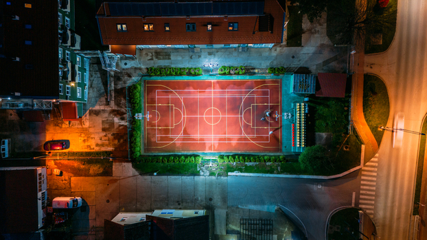 Aerial view of a basketball court bathed in radiant light contrasting sharply with the surrounding darkness Sremska Mitrovica Vojvodina Serbia. Aerial view of a basketball court bathed in radiant light contrasting sharply with the surrounding darkness Sremska Mitrovica Vojvodina Serbia.