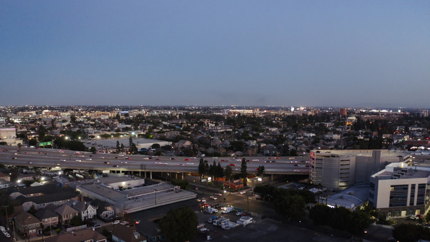 Aerial view of the Los Angeles freeway system at dusk showing dense urban sprawl residential rooftops and glowing city lights in Los Angeles California United States. Aerial view of the Los Angeles freeway system at dusk showing dense urban sprawl residential rooftops and glowing city lights in Los Angeles California United States.