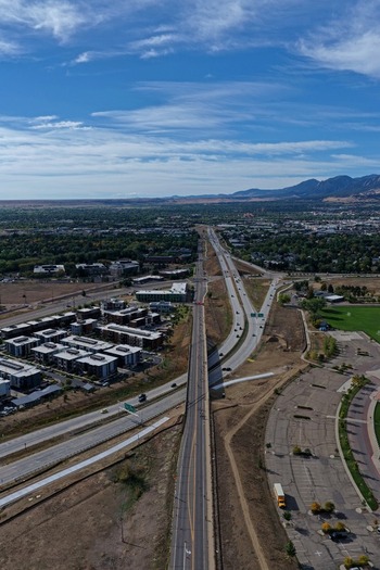 Aerial view of a highway stretching through suburban development with distant mountains under a blue sky in Boulder Colorado United States. Aerial view of a highway stretching through suburban development with distant mountains under a blue sky in Boulder Colorado United States.