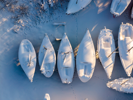 Aerial view of sailboats docked and covered in thick snow on a frozen lake during winter in Trakai Vilnius County Lithuania. Aerial view of sailboats docked and covered in thick snow on a frozen lake during winter in Trakai Vilnius County Lithuania.