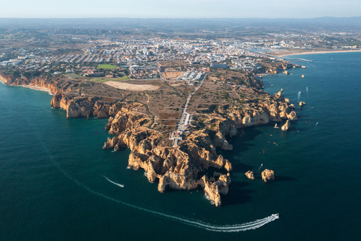 Aerial view of the dramatic limestone cliffs and rock formations of Ponta da Piedade surrounded by the Atlantic Ocean with boats near the coast of Lagos Faro District Portugal.