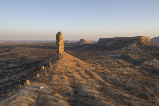 Aerial view of a solitary monolith bathed in the warm glow of sunrise standing tall amidst the arid landscape Vingerklip Namibia. Aerial view of a solitary monolith bathed in the warm glow of sunrise standing tall amidst the arid landscape Vingerklip Namibia.