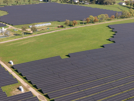 Aerial view of a large solar farm with rows of photovoltaic panels installed in a green rural landscape in Poland.