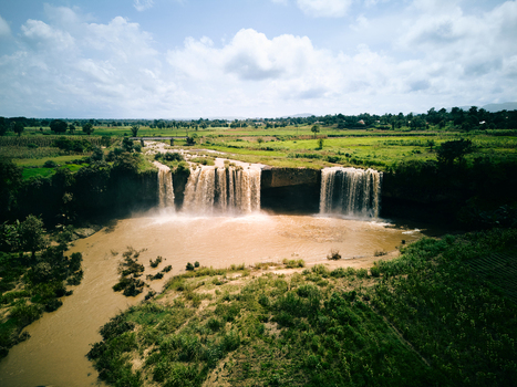 Aerial view of the wide Matsirga Waterfalls cascading into a river surrounded by lush green fields and rural landscape in Madakiya Kaduna Nigeria. Aerial view of the wide Matsirga Waterfalls cascading into a river surrounded by lush green fields and rural landscape in Madakiya Kaduna Nigeria.