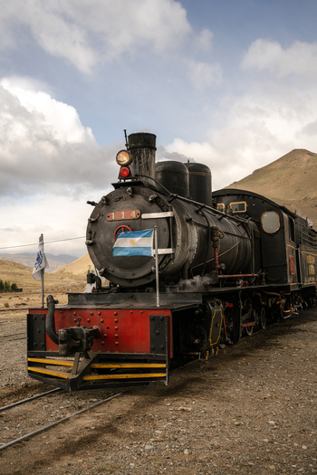View of The Trochita the historic Old Patagonian Express steam locomotive parked on tracks against a mountainous landscape in Esquel Chubut Argentina.