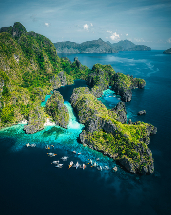 Aerial view of Big Lagoon with turquoise waters limestone cliffs and traditional outrigger boats floating in the bay El Nido Bay Philippines. Aerial view of Big Lagoon with turquoise waters limestone cliffs and traditional outrigger boats floating in the bay El Nido Bay Philippines.