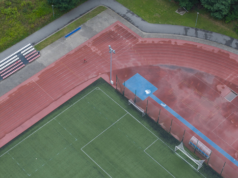Aerial view of the sports centre with a wet red running track and green soccer field after rain in Wieliczka Lesser Poland Voivode Poland. Aerial view of the sports centre with a wet red running track and green soccer field after rain in Wieliczka Lesser Poland Voivode Poland.