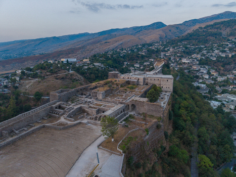 Aerial view of Gjirokaster Fortress with its historic stone walls and ruins overlooking the town and surrounding mountains in Gjirokaster Gjirokaster County Albania. Aerial view of Gjirokaster Fortress with its historic stone walls and ruins overlooking the town and surrounding mountains in Gjirokaster Gjirokaster County Albania.