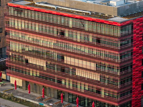 Aerial view of the Spreespeicher Promenade building with a striking red facade horizontal louvers and glass windows featuring outdoor seating and red umbrellas in Berlin Berlin Germany. Aerial view of the Spreespeicher Promenade building with a striking red facade horizontal louvers and glass windows featuring outdoor seating and red umbrellas in Berlin Berlin Germany.