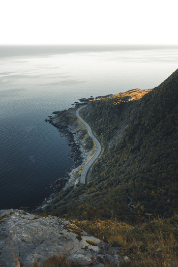 View of Reinebringen mountain trail overlooking the winding coastal road along the sea in Moskenes Nordland Norway.