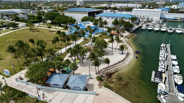 Aerial view of Peanut Island park featuring palm trees blue roofed buildings and a marina filled with white boats in Palm Beach County Florida United States.