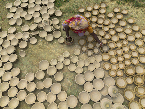 Joypurhat Bangladesh 28 September 2026 Aerial view of a potter arranging numerous clay bowls on the ground in a traditional workshop setting. Joypurhat Bangladesh 28 September 2026 Aerial view of a potter arranging numerous clay bowls on the ground in a traditional workshop setting.