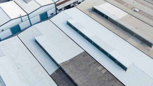 Aerial view of warehouse roofs in an industrial zone with metal structures and skylights in Milan Lombardy Italy.