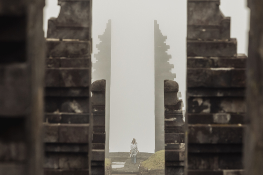 View of Cetho Temple with its iconic split stone gateway shrouded in mist and a person walking through the ancient Hindu site Kecamatan Jenawi Jawa Tengah Indonesia. View of Cetho Temple with its iconic split stone gateway shrouded in mist and a person walking through the ancient Hindu site Kecamatan Jenawi Jawa Tengah Indonesia.