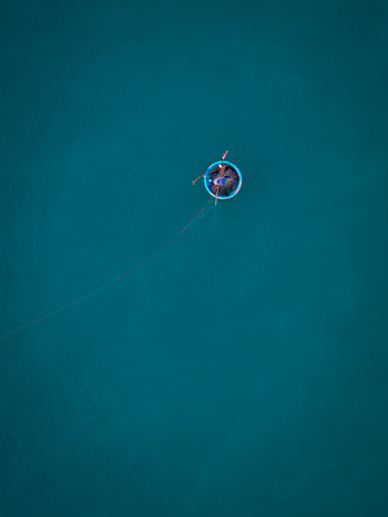 Aerial view of a traditional round basket boat with a fisherman on the calm blue sea in Vietnam. Aerial view of a traditional round basket boat with a fisherman on the calm blue sea in Vietnam.
