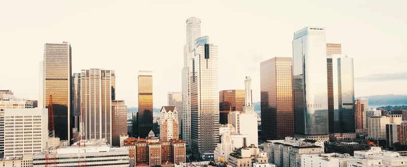 Aerial view of the Los Angeles skyline featuring modern skyscrapers reflecting the golden hour light over the urban landscape. Los Angeles California United States.