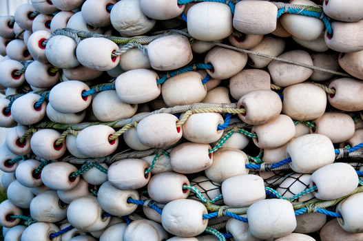 View of white plastic fishing net floats strung together with blue and green ropes in Canada. View of white plastic fishing net floats strung together with blue and green ropes in Canada.