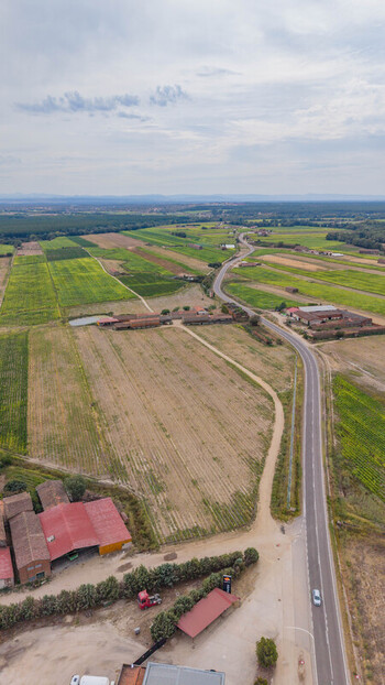 Aerial view of the rural landscape in Talayuela featuring agricultural fields farm buildings with red roofs and a winding road in Talayuela Extremadura Spain. Aerial view of the rural landscape in Talayuela featuring agricultural fields farm buildings with red roofs and a winding road in Talayuela Extremadura Spain.