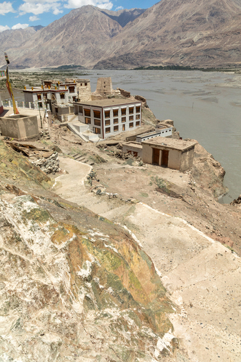 View of Charasa Gonpa monastery situated on a rocky cliff overlooking a wide river with arid mountains in the background in Charasa Ladakh India.