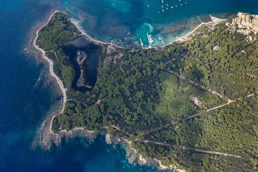 Aerial view of Ile Sainte Marguerite featuring dense pine forests a small lake rocky coastlines and clear blue waters in Cannes Provence Alpes Cote d Azur France. Aerial view of Ile Sainte Marguerite featuring dense pine forests a small lake rocky coastlines and clear blue waters in Cannes Provence Alpes Cote d Azur France.