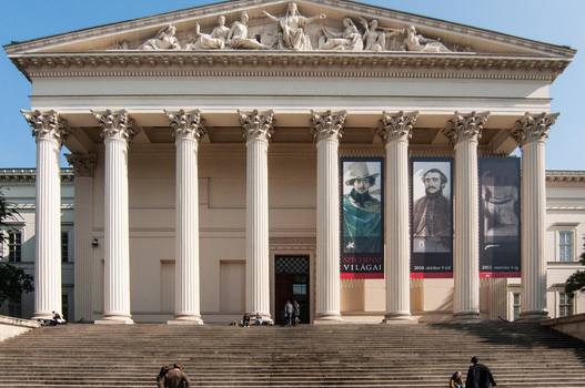 View of the Hungarian National Museum with its grand neoclassical columns pediment sculptures and wide stone staircase in Budapest Hungary.