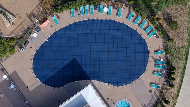 Aerial view of a swimming pool covered with a blue safety net surrounded by lounge chairs on a concrete deck in Boulder Colorado United States. Aerial view of a swimming pool covered with a blue safety net surrounded by lounge chairs on a concrete deck in Boulder Colorado United States.