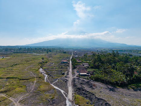 Aerial view of the volcanic landscape near Mount Semeru showing the aftermath of a catastrophic eruption with ash covered fields and rural houses in Pronojiwo East Java Indonesia.