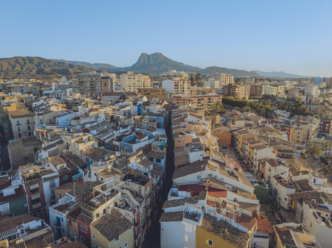 Aerial view of the colorful rooftops and narrow streets of the old town with a majestic mountain peak in the background in La Vila Joiosa Valencian Community Spain. Aerial view of the colorful rooftops and narrow streets of the old town with a majestic mountain peak in the background in La Vila Joiosa Valencian Community Spain.