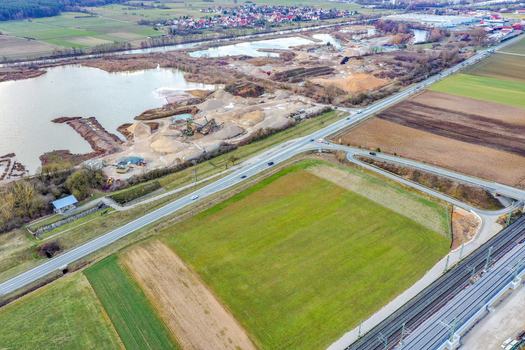 Aerial view of a gravel pit and industrial site next to a lake with green fields and the town in the distance Buttenheim Bavaria Germany. Aerial view of a gravel pit and industrial site next to a lake with green fields and the town in the distance Buttenheim Bavaria Germany.