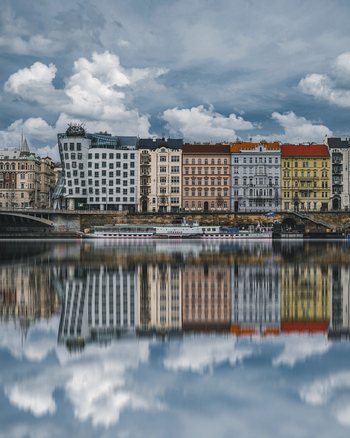 View of colorful buildings and historic architecture along the river with reflections under a cloudy sky Prague Czech Republic.