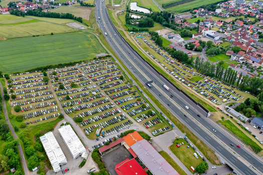 Geiselwind Germany 20 June 2025 Aerial view of the Heroes Festival Geiselwind parking area filled with cars next to the highway and green fields.