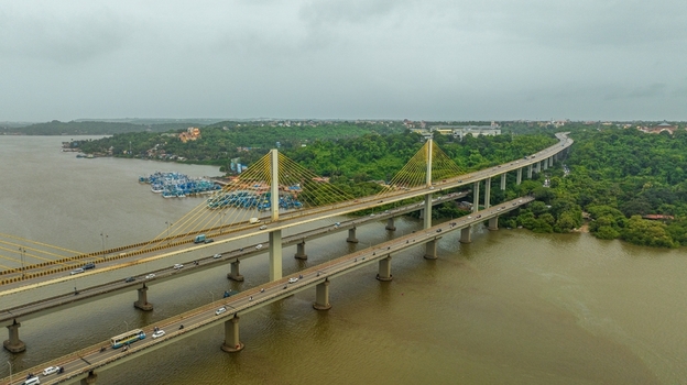 Aerial view of Atal Setu bridge spanning the Mandovi River with traffic flowing across the cable stayed structure surrounded by lush greenery in Panaji Goa India.