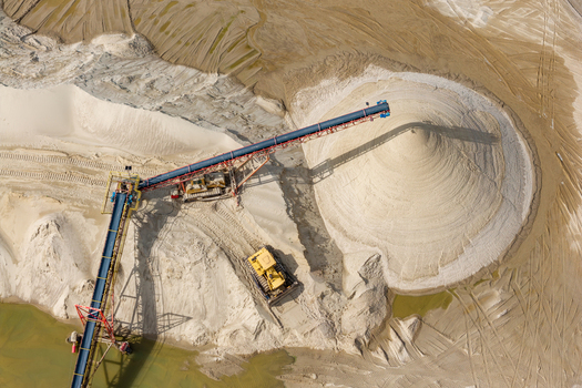Aerial view of a sand and gravel mine with a large conveyor belt system heavy machinery and piles of extracted sand in Masovian Voivodeship Poland. Aerial view of a sand and gravel mine with a large conveyor belt system heavy machinery and piles of extracted sand in Masovian Voivodeship Poland.